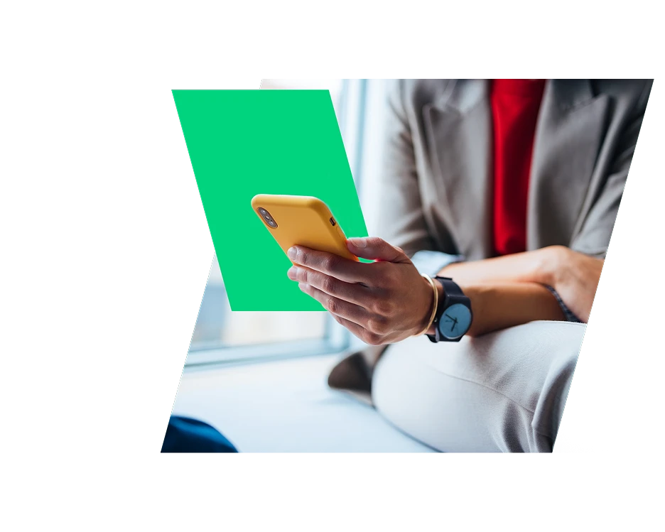 Close-up of a business professional wearing a grey suit jacket and a watch, holding a smartphone with a yellow case. A stylized bright green graphic overlay is positioned behind the phone.